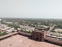 Slika prikazuje dolgo obzidje Rdeče trdnjave, vključno z vrati, kot je videti s stolpa Jama Masjid. V ozadju se vidi obzidje, ki se razteza nekaj tisoč metrov.