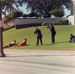 Witness hunker down on the grassy incline before the grassy knoll after the shooting
