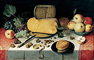 Still life with fruits, nuts, and large wheels of cheese.