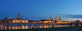 Barevná fotografie s panoramatickým pohledem na hlavní dominanty Drážďan: věže kostelů a kupole významných budov starého města na břehu Labe v nočním osvětlení