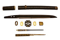 Wakisashi by Sanpin Masatoshi, early 1600s. The disassembled koshirae shows the tsuba (guard), the twin kōgai (hair pin) and the kozuka (small knife). On display at the British Museum.