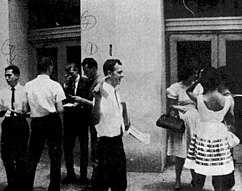Oswald is pictured passing out pamphlets on a street in New Orleans. Other men, possibly Cuban, are also passing out pamphlets behind him.