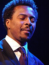 A man wearing a pin-striped suit with his eyes closed.
