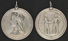 Photograph showing the two sides of a round silver medal, showing the profile of Queen Victoria on one side and the inscription "Victoria Regina", with the other side having a depiction of a man in European garb shaking hands with a man in historical First Nation clothing with the inscription "Indian Treaty 187"