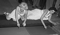 Marilyn Monroe and Jane Russell putting signatures, hand and foot prints in wet concrete at Grauman's Chinese Theater, 1953
