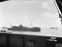 The photograph, taken from the deck of one ship, shows three nearby ships sailing in formation on the open ocean.