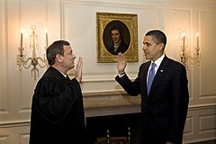 Obama (right) faces a man in judge's robe as they raise their right hands