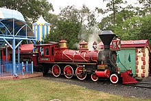 A red steam locomotive at a circus-themed train station