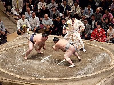 Sumo wrestlers just beginning to charge forwards after crouching down and performing an isometric press. The press enables them to charge into their opponent more powerfully, which is especially useful when the match begins.