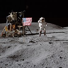 Photograph of Young in an Apollo spacesuit on the lunar surface saluting the American flag