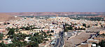 A panoramic view of a large city, with sand dunes filling the background.
