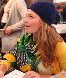 Blonde woman wearing a yellow sweater and navy blue knit hat