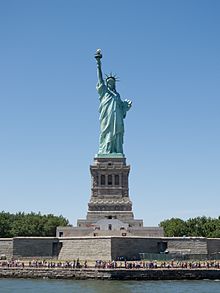 Photo of the Statue of Liberty, a giant green copper statue of a woman holding a torch