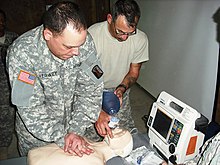 Two men perform CPR on a CPR doll