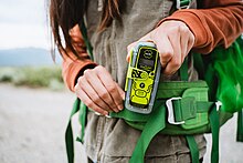 A hiker clips her personal locator beacon onto her bag.
