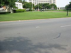 Elm Street. Le X peint sur la chaussée marque l'endroit où Kennedy a reçu le tir mortel.
