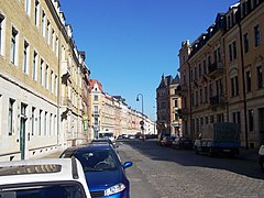 Barevná fotografie zobrazující pohled do ulice se dvěma auty