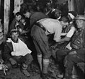 Personnels médicaux militaires traitant des blessés lors de la Première Guerre mondiale, près d'Ypres en Belgique en 1917. Le soldat à gauche est atteint du syndrome fréquent d'obusite.