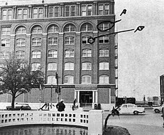 A photograph of the Texas School Book Depository, showing its view from a witness of John F. Kennedy's assassination. The window from the sixth floor is marked A, and another window from the fifth floor marked B.