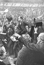 A drawing featuring William Jennings Bryan hoisted upon the shoulders of two men while a large crowd waves flags and hats.