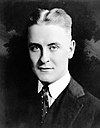 A photograph of F. Scott Fitzgerald with a slight smile and parted, slicked-back hair