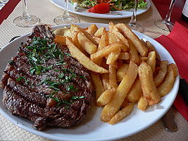 A rib steak, grilled in a griddle and served with French fries