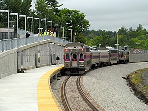 A silver and purple train at a station platform