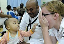 US Navy 100406-N-7478G-346 Operations Specialist 2nd Class Reginald Harlmon and Electronics Technician 3rd Class Maura Schulze play peek-a-boo with a child in the Children's Ward at Hospital Likas