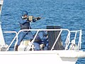 An officer holding a Type 89 rifle at the bow of a patrol boat.