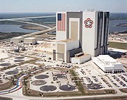 The NASA Vehicle Assembly Building in 1977. The VAB has the largest U.S. flag ever used on a building, with the Bicentennial Star opposite the flag.