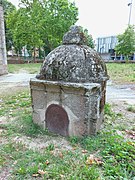 Fuente de piedra rematada en cúpula ubicada frente a la capilla.