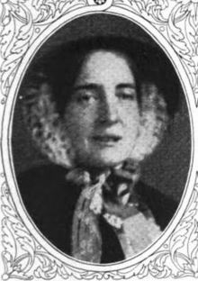 A white woman with a lacy scarf tied around her head and under her chin, in an oval frame