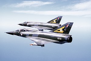 Two camouflaged military jet aircraft flying in formation