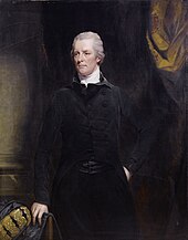 William Pitt der Jüngere zentral stehend. Hinter ihm ein Vorhang drapiert vor einer Wand. Pitt trägt einen schwarzen Anzug, seine rechte Hand ruht auf einem Stuhl, sein Gesicht ist im Vergleich zu früheren Darstellungen bereits deutlich gealtert.