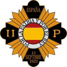 The yellow and black emblem of the Unión Patriótica. The Spanish flag is in the middle of the emblem, contained in a circle shape.