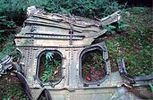 A fragment of Flight 93's metal fuselage with two windows, sitting in a forest