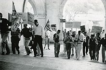 Men marching up the Frary Dining Hall steps carrying handwritten protest signs