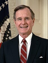 Official portrait of George H. W. Bush standing in front of an American flag