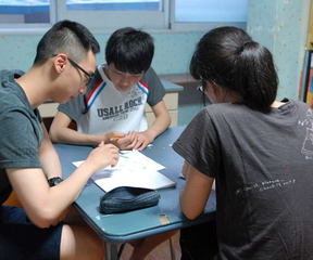 Photo of a man tutoring two children