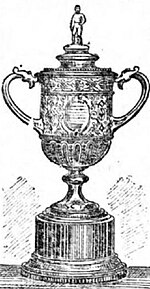 A trophy, silver in colour and topped by a figure of a footballer, on an ebony plinth