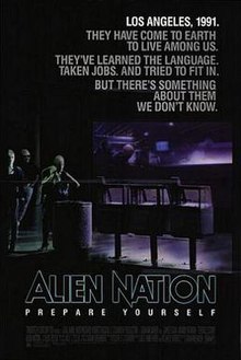 A black poster. Above in bold letters are the lines: "Los Angeles, 1991." "They have come to earth to live among us." "They've learned the language." "Taken jobs." "And tried to fit in." "But there's something about them we don't know." Below, in large typeface is the line: "Alien Nation" and in smaller typeface, the line: "Prepare Yourself," with the film credits underneath. In the background are three extraterrestrials standing on a street corner. One of the figures is a female standing next to a waste basket and three newspaper stands, holding a jacket over her shoulders. Behind her is a bar that features alien typography on its walls. Two extraterrestrials who are hanging out inside the bar, can be seen through its glass window.