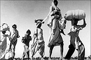 An old Sikh man is carrying his wife. Over 10 million people were uprooted from their homeland and traveled on foot, bullock carts and trains to their promised new home.