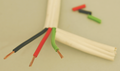 Broad white-coated cable, cut away to show green, red and black coated wires