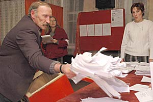 An election official places ballot papers on the table as other officials prepare to count the votes at a polling station in Tolochin during parliamentary elections in Belarus, 17 October 2004. (Lubomir Kotek)