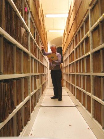 A man looking at a record in a large record library