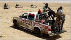 Rebel fighters ride in vehicles as they drive in the desert along the Benghazi-Ajdabiyah road