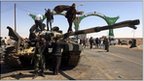 Libyan rebels gather on a destroyed tank in Ajdabiya on 26 March 2011