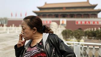 A tourist smokes in front of Beijing's Tiananmen Gate