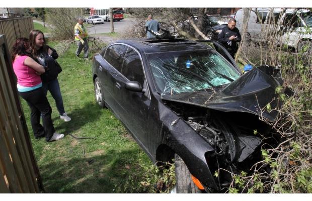 Two young woman look at a car that crashed into some bushes after striking a tree along Cahill Dr. is towed away in Ottawa on Sunday, May 8, 2011. The driver, a 23-year-old man, was in hospital in serious but stable condition.