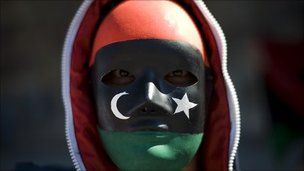 Man wearing a mask painted with the flag of the old Libyan monarchy